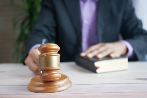 person with hand on book holding gavel